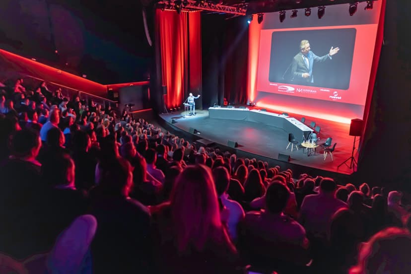 Escenario iluminado con luces y una presentación en pantalla